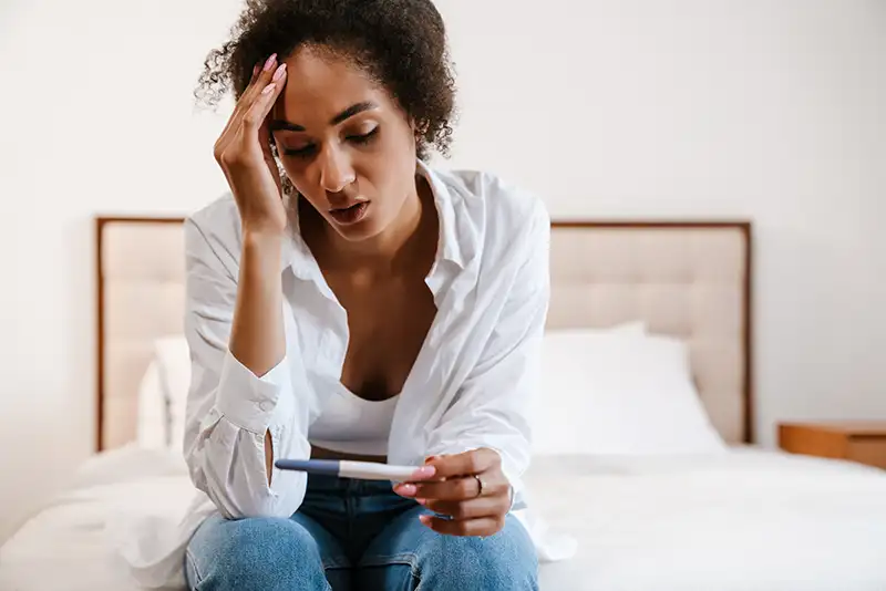 Woman looking at a pregnancy test while seeking answers about trouble conceiving and female infertility at Positive Steps Fertility
