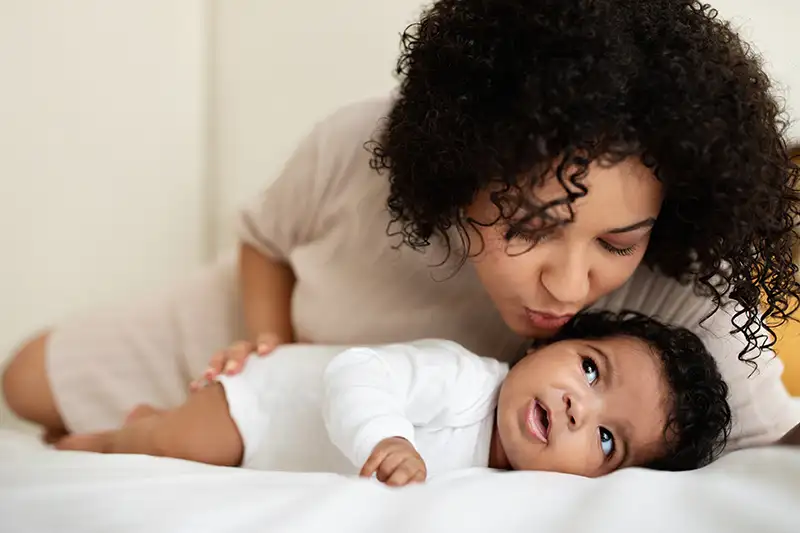 Mother kissing her newborn baby after her embryo transfer with Positive Steps Fertility