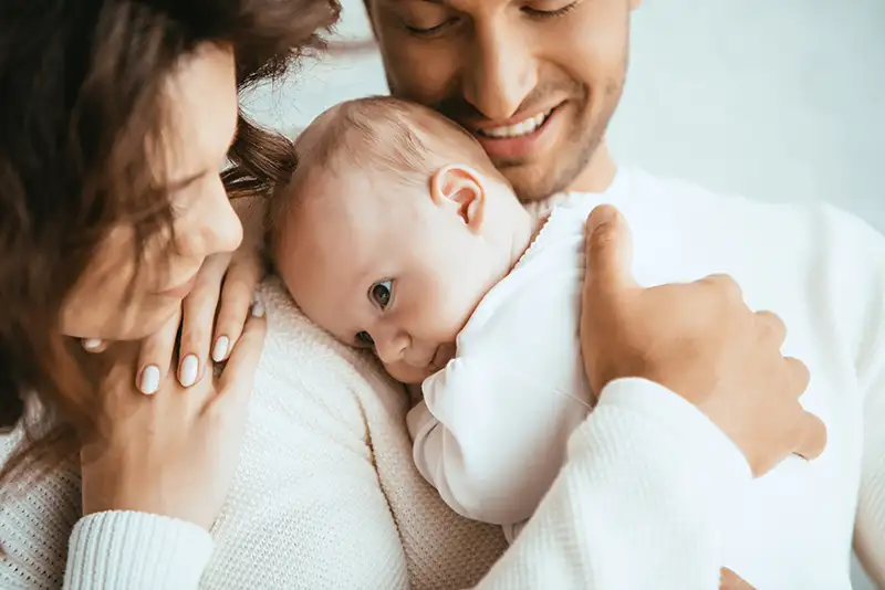 Happy couple with their newborn after fertility journey with Preimplantation Genetic Testing (PGT) at Positive Steps Fertility