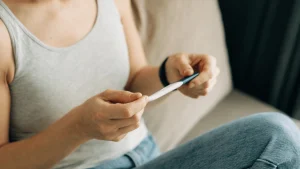Woman holding a pregnancy test while considering fertility testing