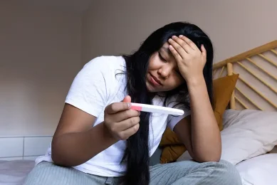 Woman taking a home pregnancy test while navigating low egg count (diminished ovarian reserve) and fertility concerns