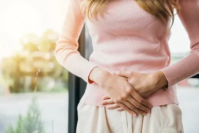 Woman holding her lower abdomen to represent blocked fallopian tubes and female infertility during a fertility consultation at Positive Steps Fertility