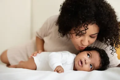 Mother kissing her newborn baby after her embryo transfer with Positive Steps Fertility