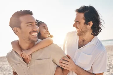 Gay male couple with their child representing family building through third-party reproduction at Positive Steps Fertility